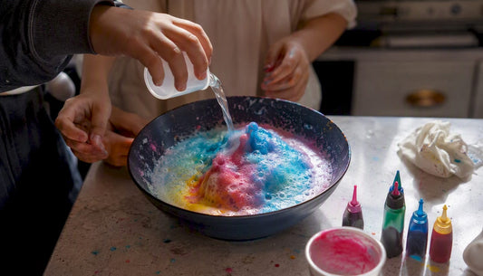 Children's hands drip vinegar onto colorful baking soda in tray