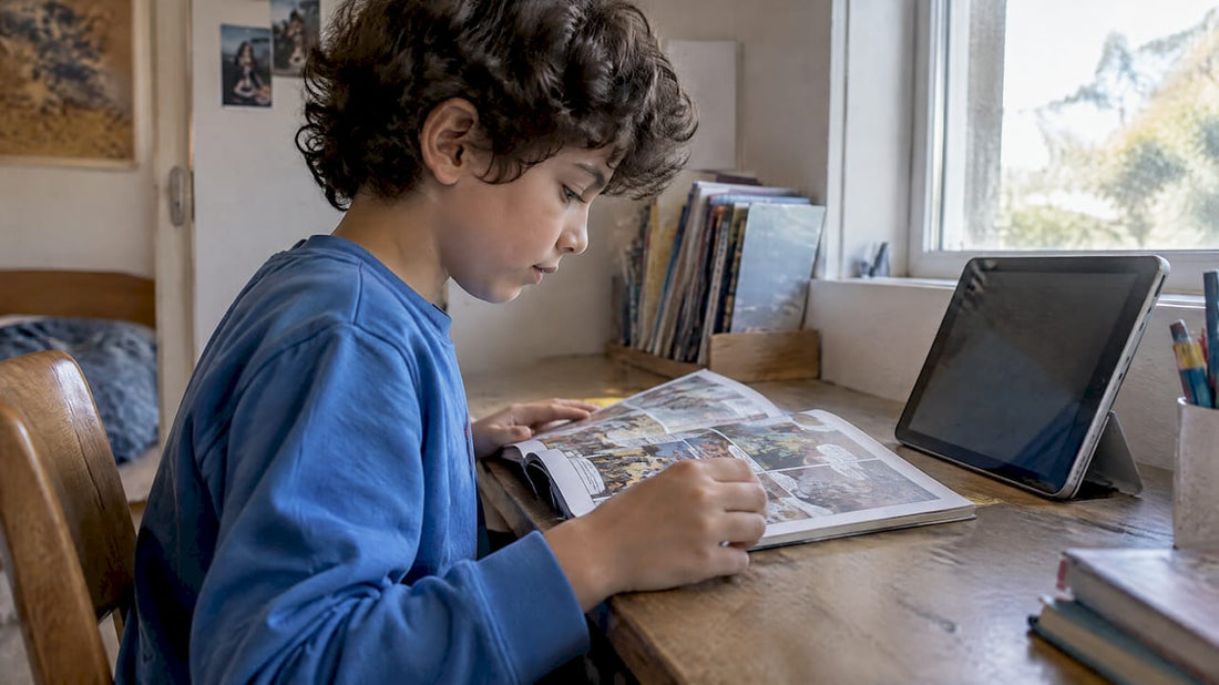 Child reading a comic beside a tablet